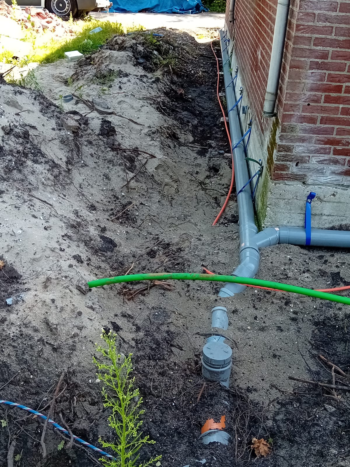 Loodgieter legt nieuwe rioleringsleidingen aan in een sleuf in Scherpenzeel